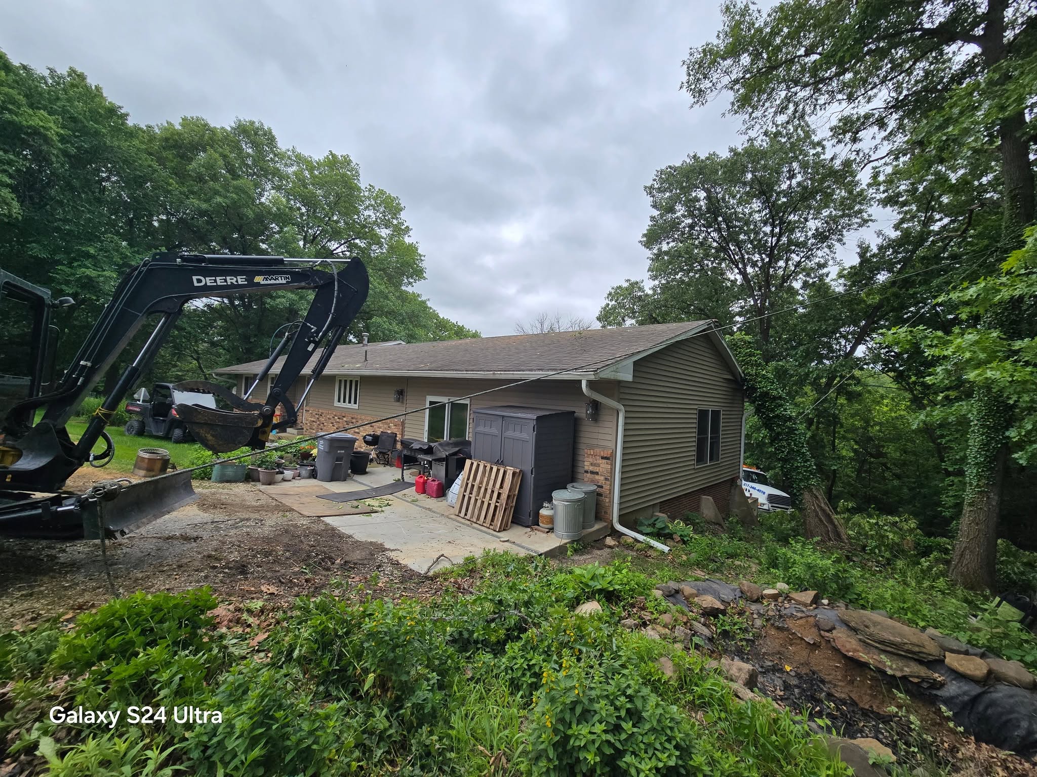 Another angle of the same property after the fallen tree was removed, with excavator and remaining debris visible