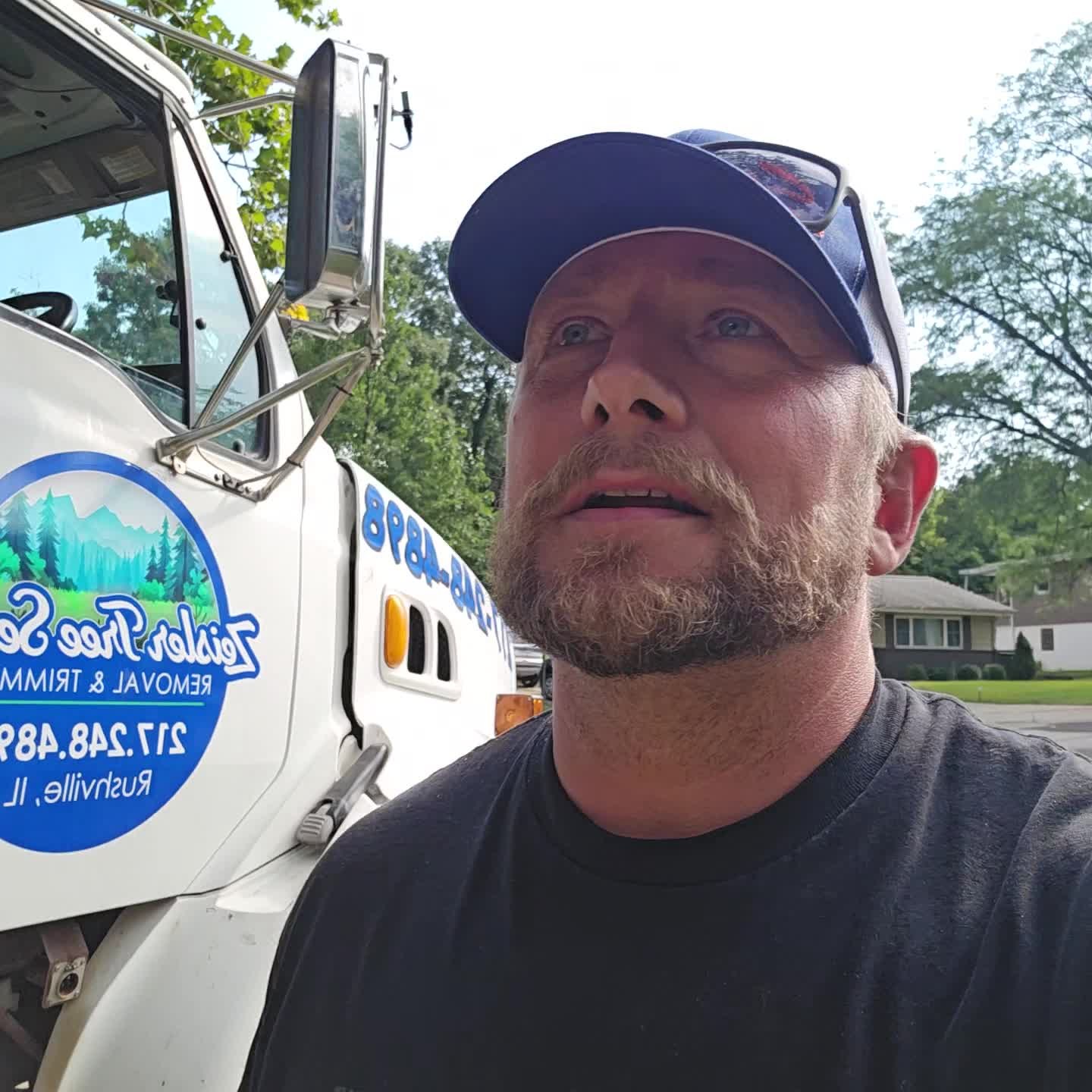 Todd Zeisler beside the tree service truck on a job site